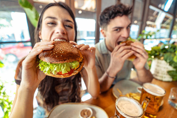 istock Couple eating fresh burger sitting at pub restaurant table 2155130725