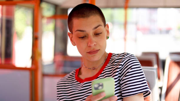 istock Young, short-haired woman in a bus surfing the net 2155131162