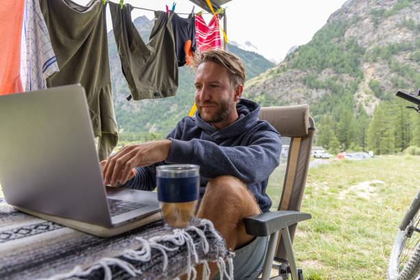 istock Man Working on Laptop at Campsite with Scenic Mountain Background 2155136428