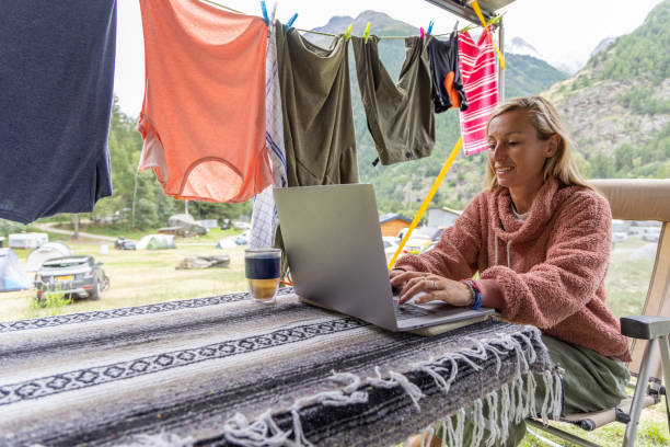 istock Woman Smiling While Working on Laptop at Campsite 2155136523