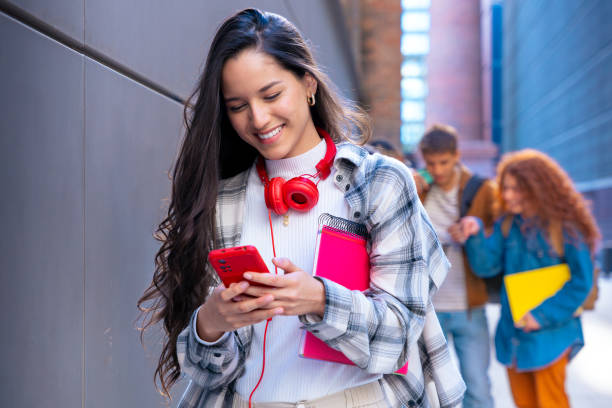 istock Happy young latin woman browsing the internet using mobile device outdoors. 2155137524