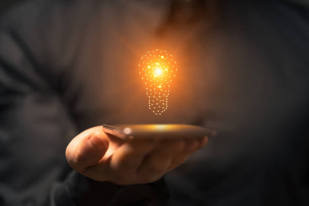 istock Idea concept with hand holding smartphone with glowing light bulb 2155138955