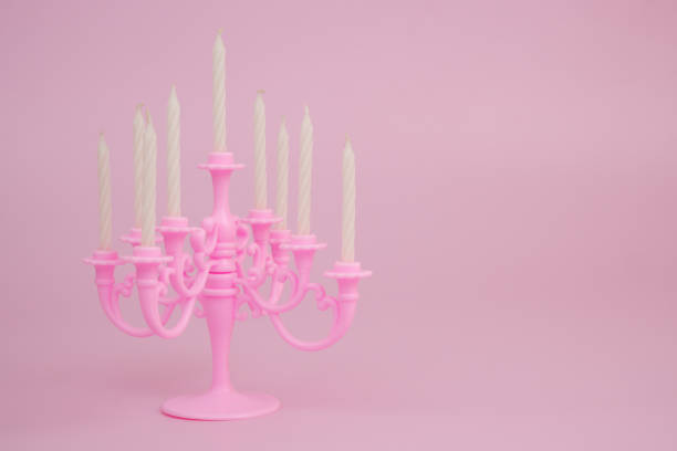 Pink candelabra with white candles on pink background. Copy space for text.