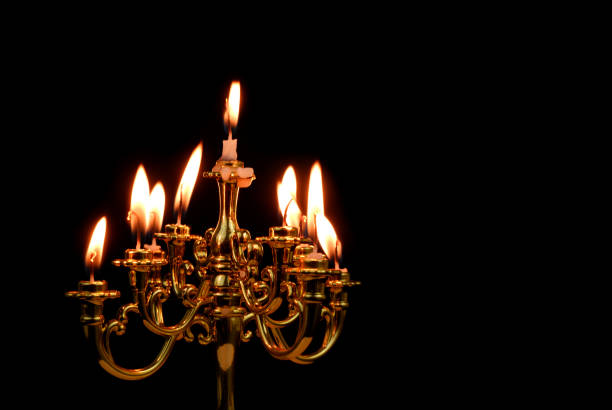 Golden candelabra with many white burning candles isolated on black background.