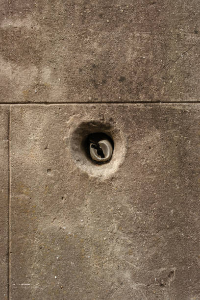 Part of an old dirty concrete wall with a hole in it.