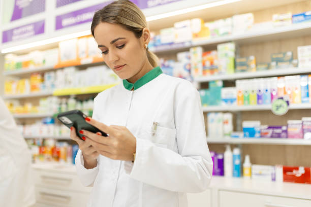 istock Young woman pharmacist at her workplace using mobile phone 2155147996