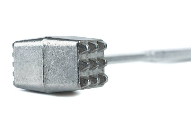 Selective focus of a metal meat tenderizer hammer. The focus is in the foreground, the background is blurred. Kitchen utensils.