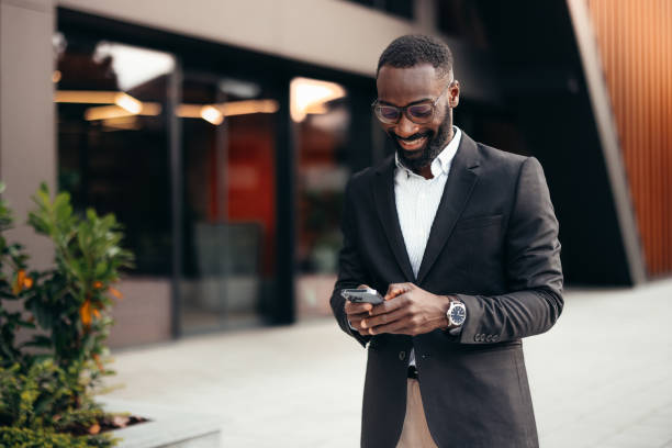 istock Smiling business man using smartphone outside the office 2155154296
