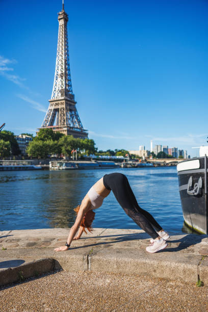 istock Mature woman taking up outdoor exercise, stretching on pier at Paris waterfront 2155156229