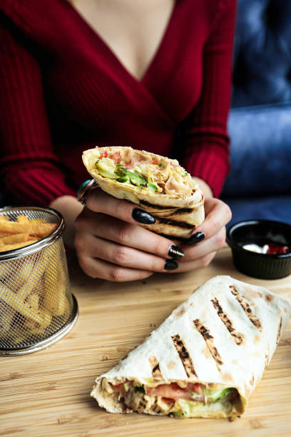 istock Woman Holding Sandwich on Wooden Table 2155158101