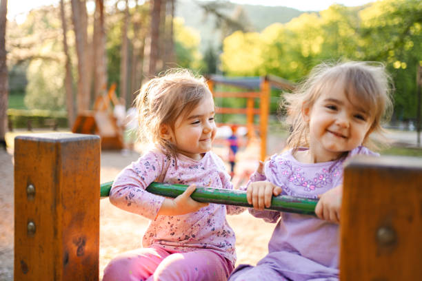 istock Cute twin sisters on the playground 2155160481