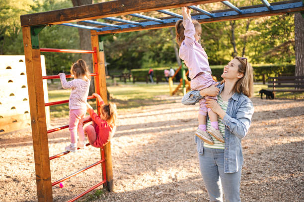 istock Smiling mom helps her cute daughter climb the playground 2155160489