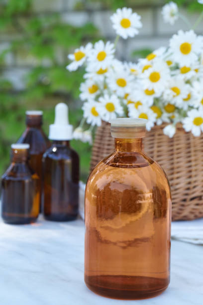Composition with chamomile flowers and cosmetic bottle of essential oil. Side view.