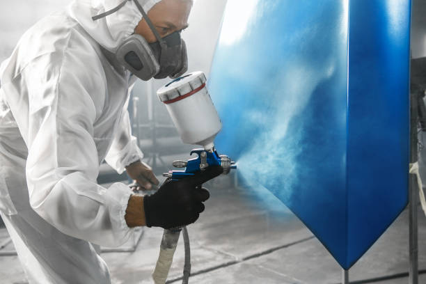 istock Professional bodywork, male car painter in protective mask and workwear apply few layer paint from spray gun to automobile body parts in garage booth. 2155165794