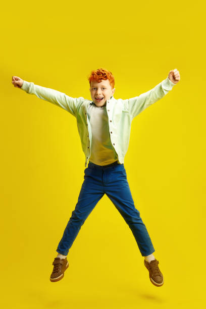 istock Happy Red Haired Little Boy Jumping Up Cheerfully on Yellow Isolated 2155166873
