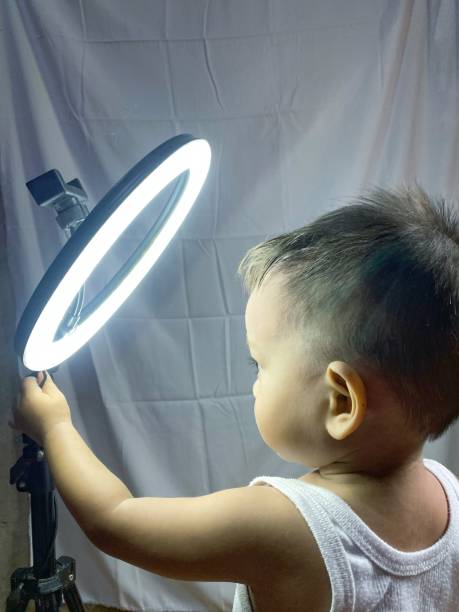 istock boy holding a tripod ring light, in a shooting room 2155167616