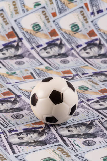 istock Miniature soccer ball with $100 bills in the background 2155176626
