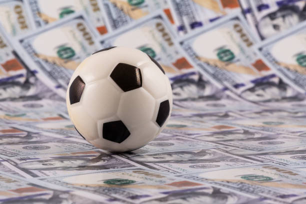 istock Miniature soccer ball with $100 bills in the background 2155176627