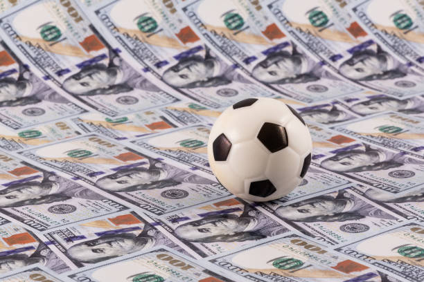 istock Miniature soccer ball with $100 bills in the background 2155176637
