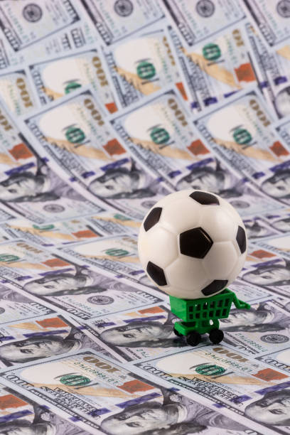 istock Miniature soccer ball with $100 bills in the background 2155176654
