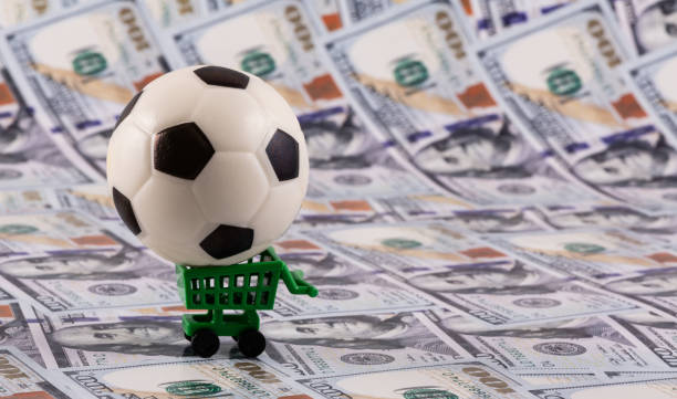 istock Miniature soccer ball with $100 bills in the background 2155176659