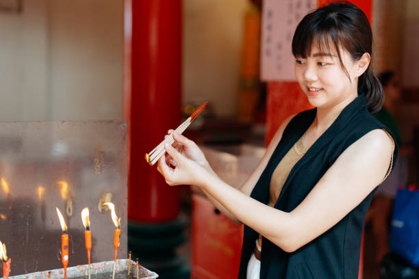 istock Asian woman burning incense sticks at Buddhist temple 2155177293