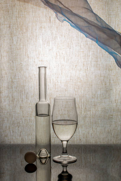 Bottle and glass of white wine on yellow background