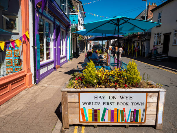 Shops and shoppers in Castle Street, Hay-on-Wye, on the English-Welsh border, which a foreground wooden flower planter brands as “the world’s first book town”.