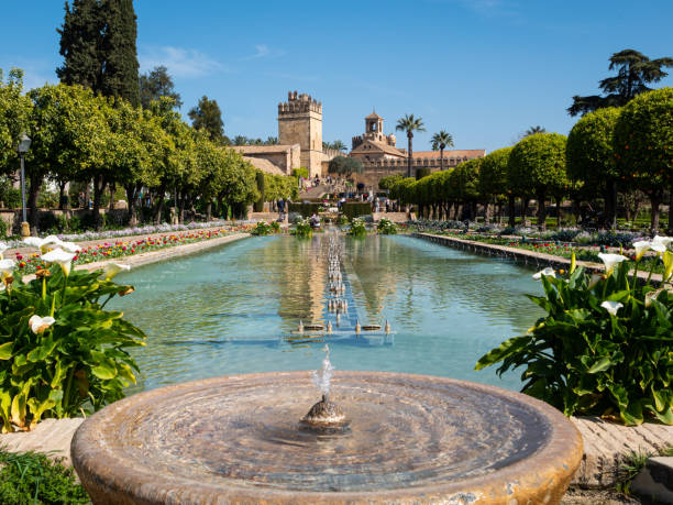 Trees and colourful flowers line the water features in the gardens of the fortified Alcázar de los Reyes Cristianos (Castle of the Christian Monarchs) in Córdoba, Andalucia.