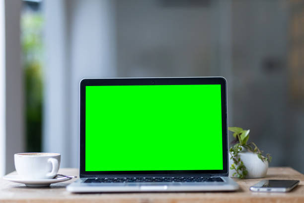 istock Mockup of laptop computer with empty screen with coffee cup and smartphone on table of the coffee shop background,Green screen 2155180677