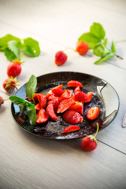 fresh fruit salad of ripe strawberries on a light wooden table