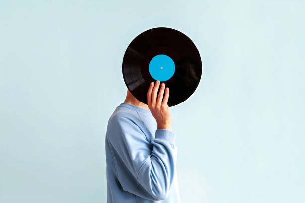 istock Man in  blue sweatshirt covers his face with vinyl record on blue background 2155183199