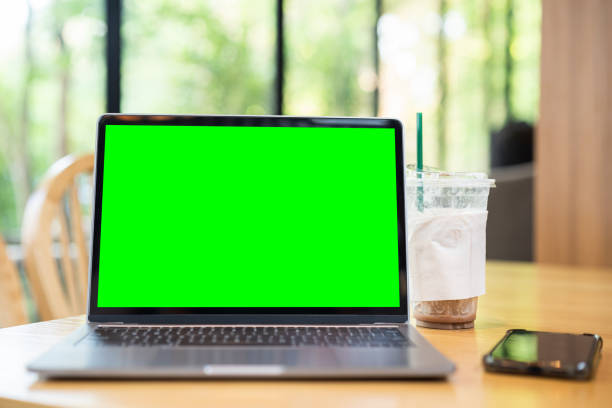 istock Mockup of laptop computer with empty screen ,ice coffee and smartphone on table side the window in the coffee shop at the cafe,Green screen 2155185776