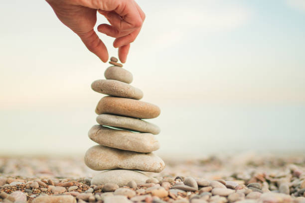 istock A hand is reaching for a stack of rocks, which are arranged in a pyramid shape 2155186223