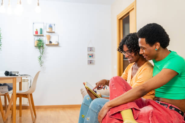 istock Gay couple using digital tablet sitting at home 2155187357