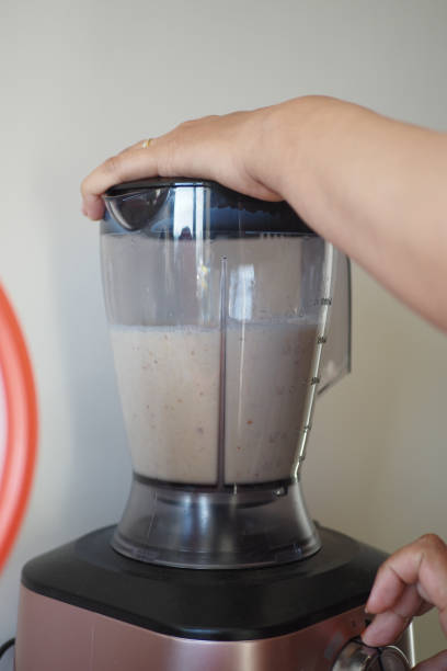 istock Person making smoothie in blender with food and liquid in kitchen appliance 2155191405
