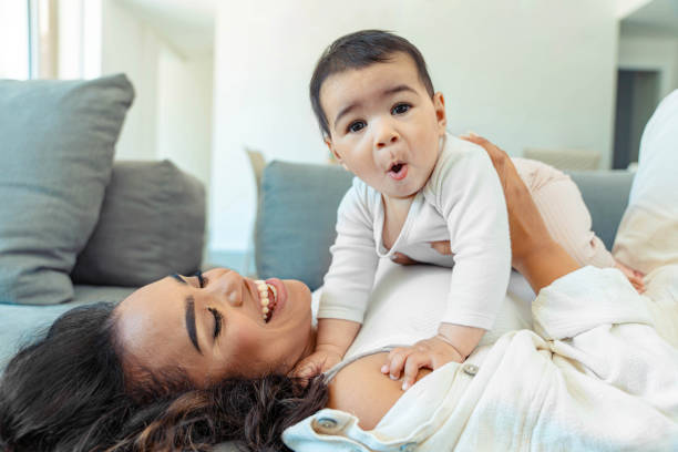istock Happy black mother playing with daughter lying on sofa - Delightful mom relaxing with baby indoors - Family and childhood life style concept 2155192018