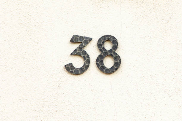 house number 38 in metal at white painted plaster wall