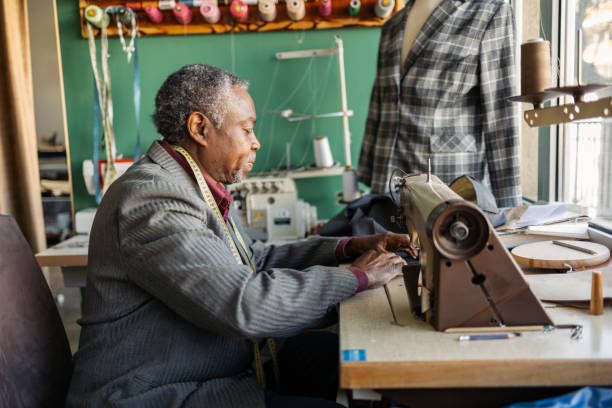 istock Latin senior man working as a tailor. He is working in the small tailoring shop. 2155201425