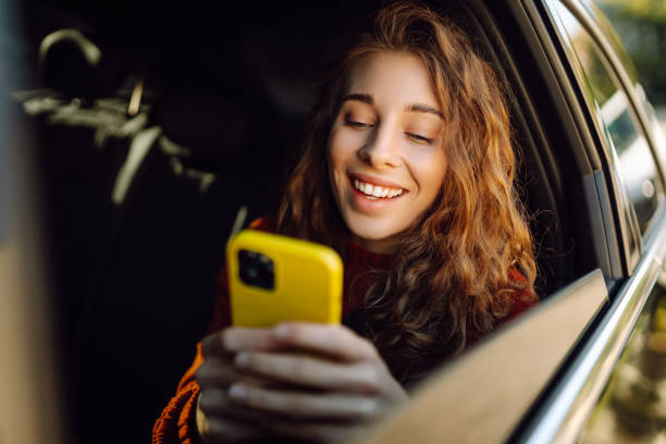 istock Young beautiful woman passenger uses a smartphone sitting on car. 2155202739
