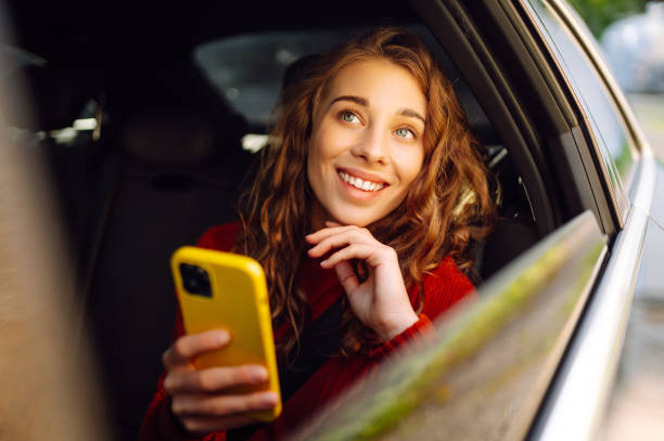 istock Young beautiful woman passenger uses a smartphone sitting on car. 2155202763