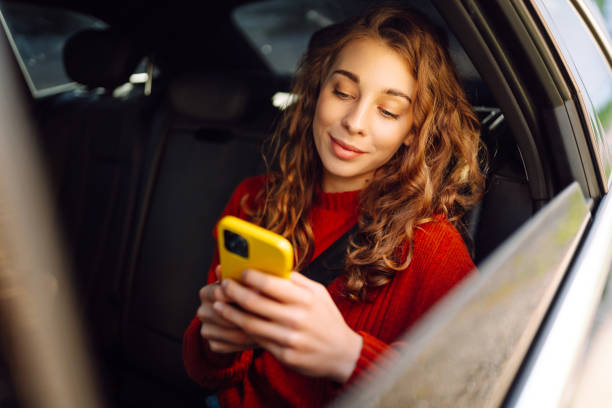 istock Young beautiful woman passenger uses a smartphone sitting on car. 2155202775