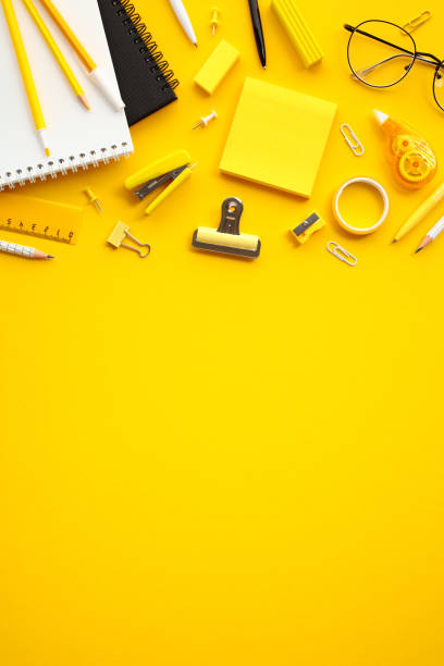 istock Vibrant office supplies on yellow background. Top view essential office stationery including pencils, notepad, sticky notes, paper clips, stapler, scissors and eyeglasses 2155208057