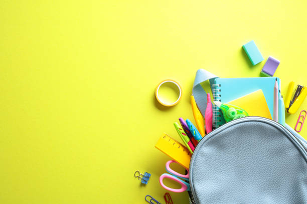 istock Back to School concept: Colorful school supplies including backpack, notebooks, pencils, scissors, and more against a vivid yellow backdrop. Perfect for educational themes. 2155208290