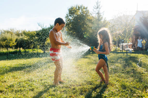 istock Children refreshing with garden hose in the yard 2155210650
