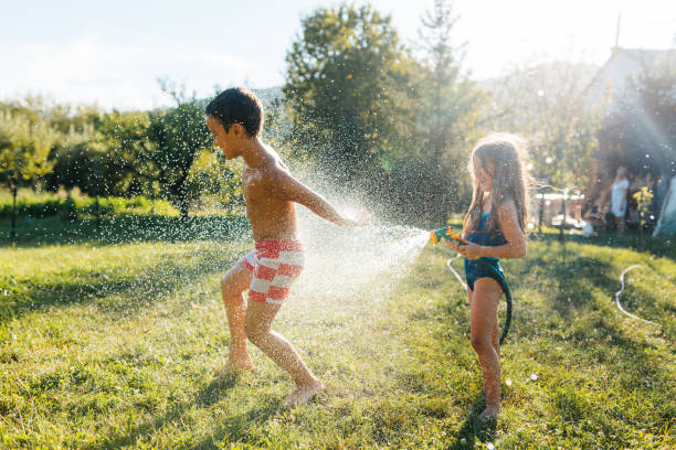 istock Children refreshing with garden hose in the yard 2155210662