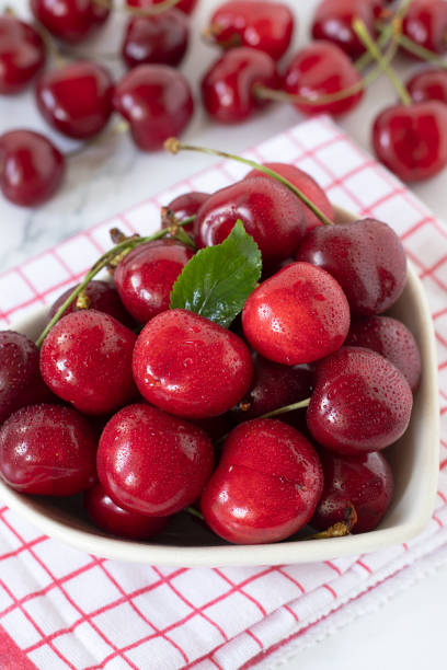 istock Red cherries with water drops in heart shaped bowl, close-up 2155211023