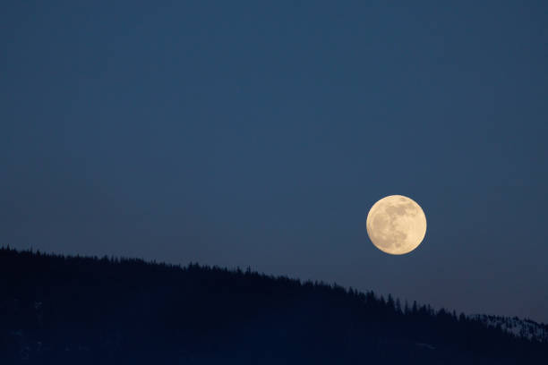 A view of the full moon rising over the horizon in Nelson, British Columbia, Canada.