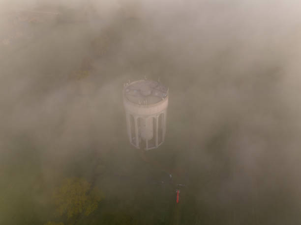 Aerial view of a solitary water tower immersed in a thick, soft fog at the break of day