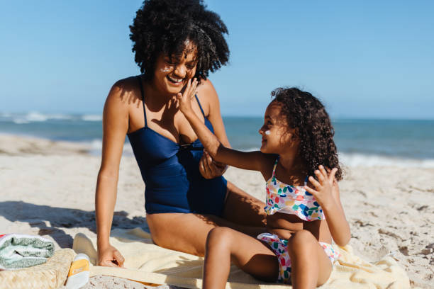 istock Mother and daughter applying sunscreen on a sunny beach day 2155223632